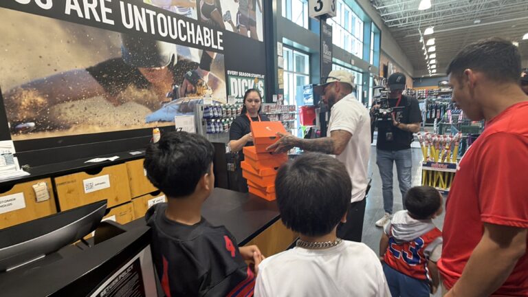 Coach Andrew handing out boxes of new cleats to kids