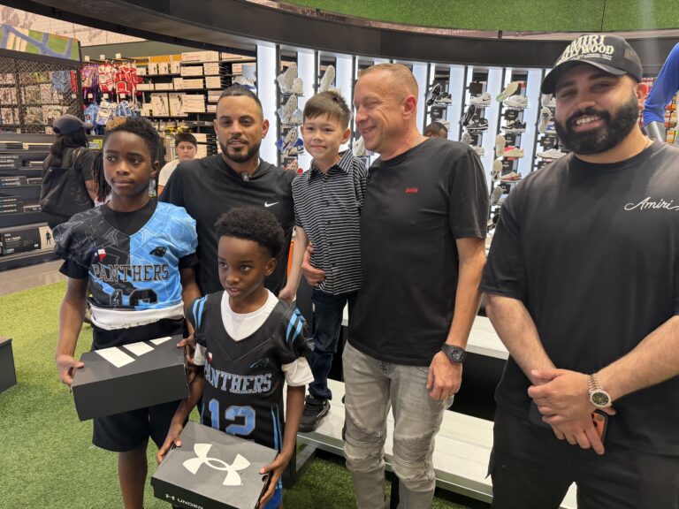 Kids holding boxes of new cleats donated by Iron Walk For Kids